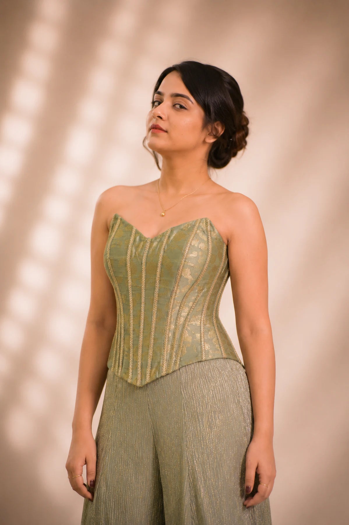 Close-up of sage green brocade corset bodice with gold piping detail, occasion wear by Label Neha Sinha